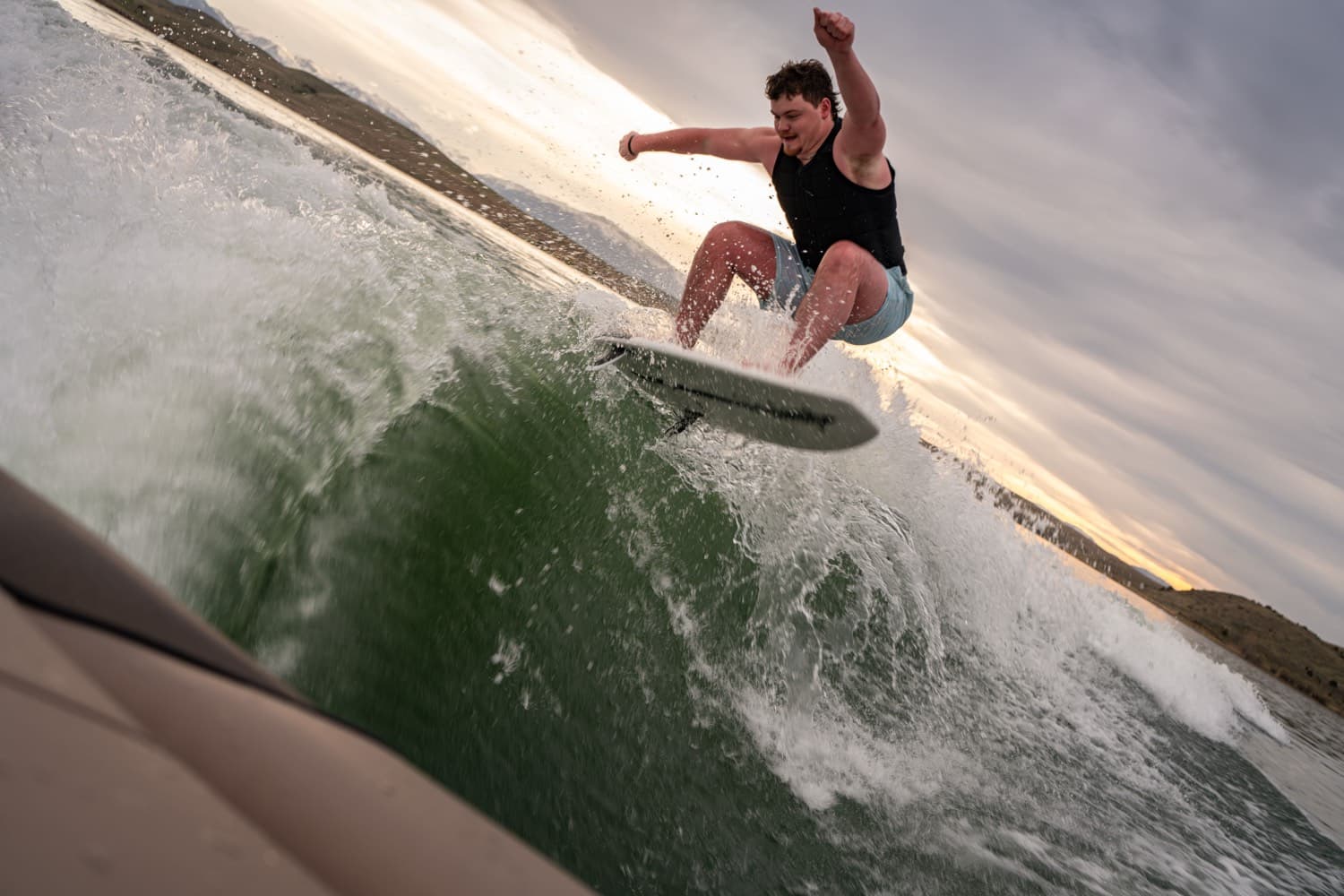 A rider coming off the top of the wake, board out of the water, sunset behind.